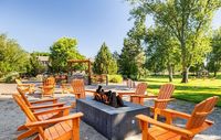 Inviting outdoor space with vibrant orange chairs surrounding a cozy fire pit, nestled in a lush green setting perfect for relaxation.