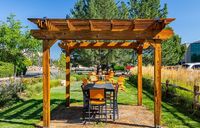 Charming outdoor patio with a wooden pergola, cozy seating, and lush green surroundings, perfect for relaxing gatherings.