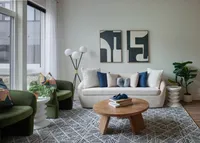Montgomeryville apartment iving room with a white sofa, green chairs, abstract wall art, and a wooden coffee table.