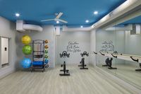 Community apartment fitness room with spin bikes, exercise balls, resistance bands, mirrors, and a ballet barre.