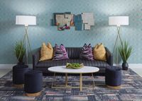 Chic living room with plush black sofa, vibrant pillows, modern art, and elegant decor.
