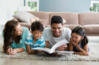 Happy family enjoying reading together in a cozy living room with comfortable carpet and stylish sofa.