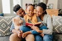 Warm family moment on a cozy couch, with parents and child smiling and reading together, surrounded by stylish decor and plush accents.