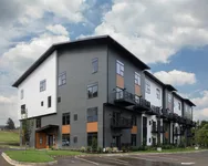 Corner view of theexterior of Foundry Flats, Emmaus, PA with gray and white siding, balconies, large windows, and landscaped grounds.