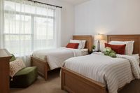 Bedroom with two twin beds, striped bedding, accent pillows, large window, and cozy décor.
