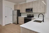 Modern Emmaus, PA apartment kitchen with light wood cabinets, stainless steel appliances, white countertops, and black faucet.