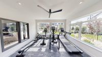 Bright and modern gym room with sleek exercise equipment and large windows offering a picturesque garden view.