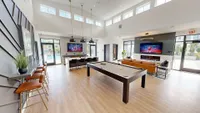 Modern lounge area featuring a cozy seating arrangement, sleek pool table, and abundant natural light, perfect for entertainment and relaxation.