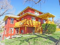 Inviting two-story brick home with warm wooden accents and a sunny porch.