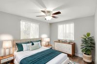 Bright and airy bedroom featuring elegant decor, a cozy bed with plush pillows, and abundant natural light from large windows.
