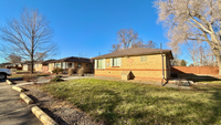 Charming brick ranch-style home with large front yard in a serene neighborhood setting, bathed in sunlight.