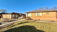 Charming brick apartment exterior with a landscaped front yard under a clear blue sky.