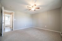 Bright and spacious bedroom with soft carpet flooring and modern ceiling fan, exuding comfort and style.