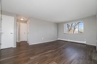 Spacious modern living room with sleek hardwood floors and large window providing plenty of natural light.