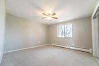 Bright and spacious bedroom with plush carpeting and a ceiling fan, featuring a large window with a serene view.