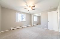 Bright and airy bedroom featuring plush carpeting, large window with natural light, and a mirrored closet for added elegance.