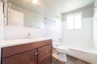 Bright and modern bathroom featuring a sleek wood vanity, pristine bathtub, and elegant tilework.