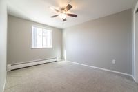Bright and inviting empty room with neutral walls, soft carpet, and a modern ceiling fan, ready to be personalized.