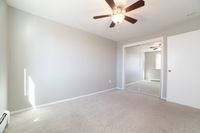 Bright and airy bedroom with plush carpeting, mirrored closet doors, and a modern ceiling fan.