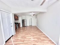 Bright, open-concept living area with sleek wooden flooring, modern kitchen with stainless steel appliances, and ample natural light.