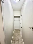 Bright, inviting hallway featuring elegant tile flooring and a modern light fixture, leading to a convenient closet space.