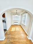 Charming dining area featuring polished hardwood floors, elegant archway, and contemporary lighting.
