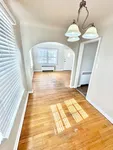 Bright and inviting hallway with elegant archway and polished hardwood floors, perfect for a stylish entry into your new home.