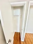 Bright and spacious closet with elegant wooden flooring, highlighting ample storage space in a modern apartment.