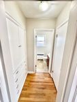 Bright hallway with elegant hardwood floors and built-in storage leading to a modern bathroom with natural lighting.