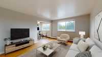 Bright open-plan living room with cozy seating, modern TV setup, and dining area, enhanced by large windows and stylish décor.