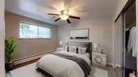 Inviting bedroom with elegant decor featuring a plush bed, modern ceiling fan, and ample natural light.