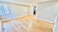Bright and inviting room with elegant hardwood flooring, large window for natural light, and soft neutral walls, perfect for versatile living space.