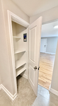 Bright apartment with elegant hardwood floors, open storage closet with multiple shelves, and sleek modern finishes.