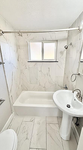 Elegant bathroom featuring a modern bathtub with sleek fixtures, a chic pedestal sink, and bright natural lighting.