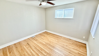 Bright, spacious room with polished hardwood floors and natural light from a wide window, perfect for a cozy bedroom or home office.