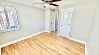 Bright and airy room with elegant hardwood floors, ceiling fan, and ample natural light from a large window.