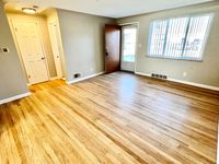 Bright and inviting living room with elegant hardwood floors, large window, and modern door creating a warm, welcoming atmosphere.