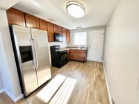 Modern kitchen with stainless steel appliances, warm wood cabinetry, and sleek laminate flooring, bathed in natural light.