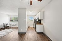 Modern kitchen with stainless steel appliances, bright living area, and elegant wood flooring
