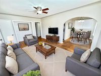 Charming living room with elegant gray sofas, wooden coffee table, and a stylishly integrated dining area featuring a round table and plush chairs under ambient lighting.