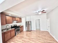 Charming apartment kitchen with modern stainless steel appliances, sleek wooden cabinets, and elegant hardwood flooring.