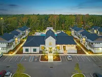 Aerial view of leasing office and community with trees behind