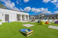 Green lawn space with coloerful seating options and outdoor games