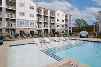 Elegant apartment complex with poolside lounge chairs and modern design.