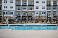 Chic apartment building facade with a pristine pool and comfortable sun loungers.