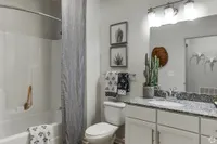 Sleek bathroom with modern fixtures, elegant granite countertop, and decorative touches.