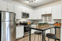 Elegant modern kitchen featuring stainless steel appliances, white cabinets, and a chic breakfast bar.