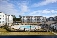 Aerial view of a modern apartment complex with a pristine pool area surrounded by lush landscaping.