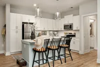 Bright modern kitchen with white cabinetry, stainless steel appliances, and a central island with bar stools.