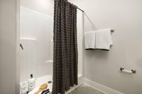 Inviting bathroom with a stylish shower, textured curtain, and fresh white towels.